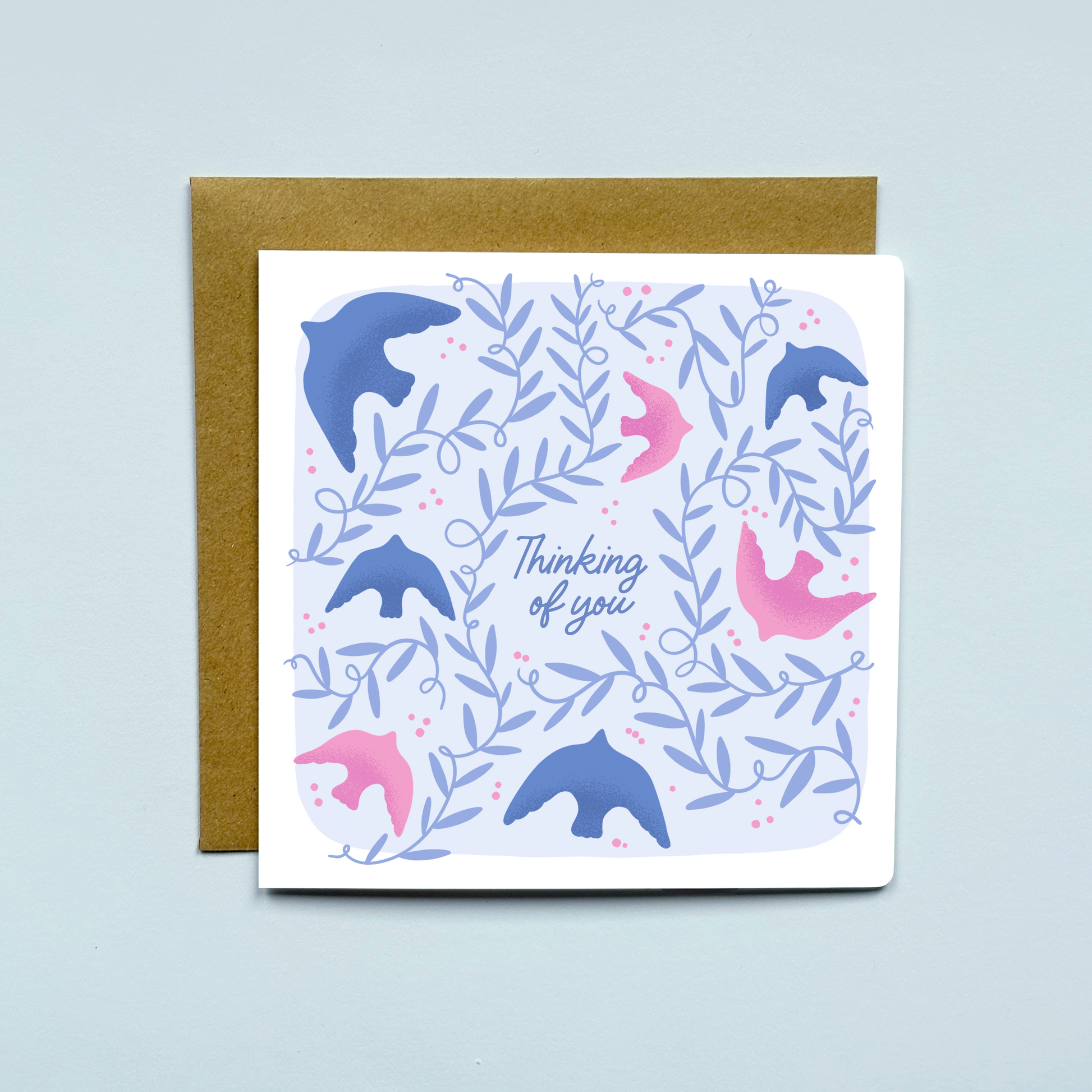 Greeting card with birds and leaves on a light blue background, placed on a kraft brown envelope