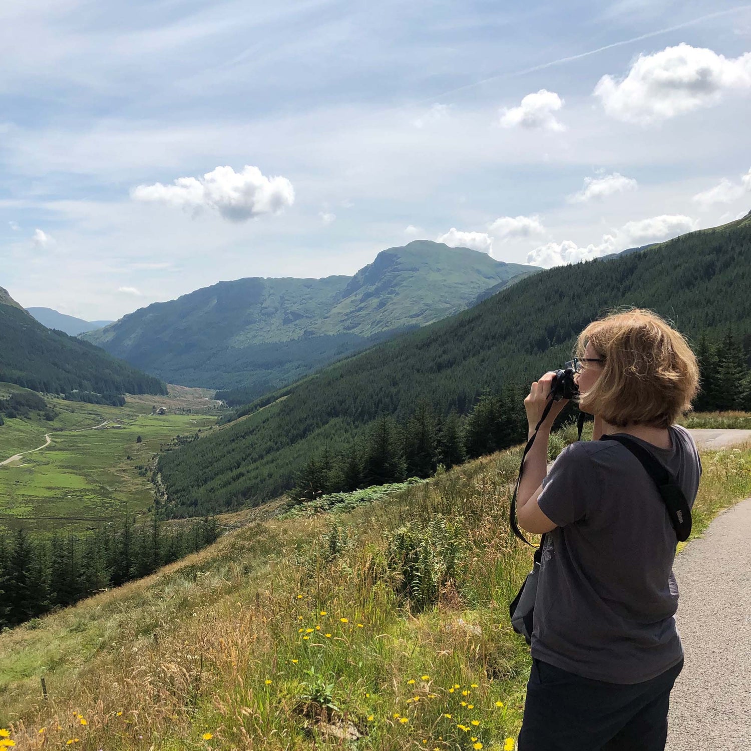 Person taking a photograph of a scenic mountain landscape